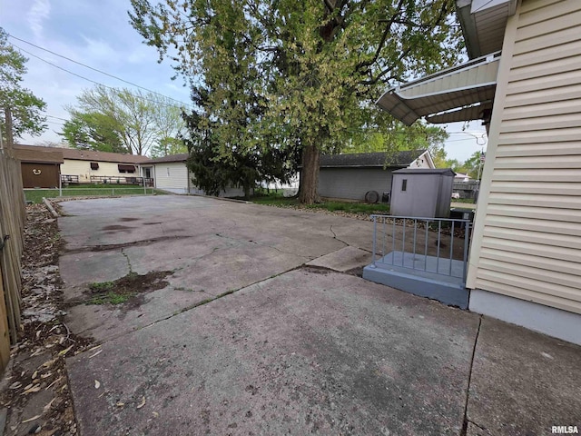 view of patio featuring an outdoor structure, a shed, and fence