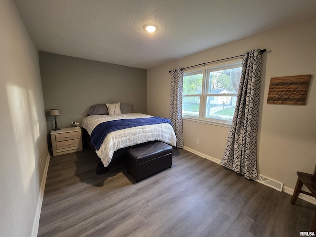 bedroom with visible vents, wood finished floors, and baseboards