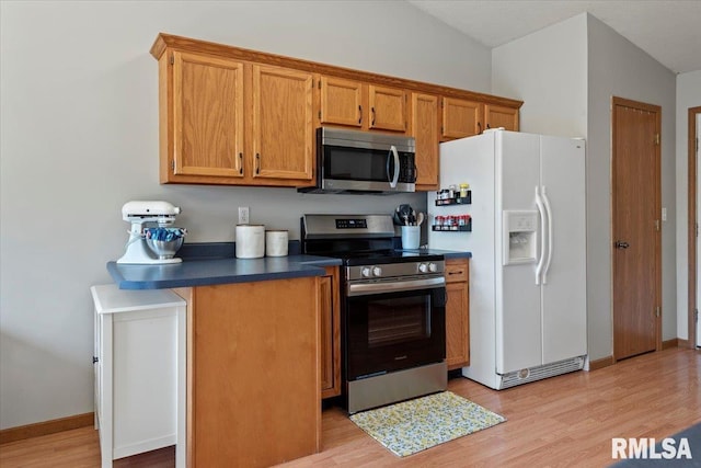 kitchen with dark countertops, brown cabinetry, stainless steel appliances, baseboards, and light wood-type flooring
