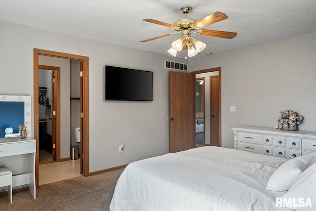 bedroom featuring a walk in closet, ceiling fan, light colored carpet, visible vents, and a closet