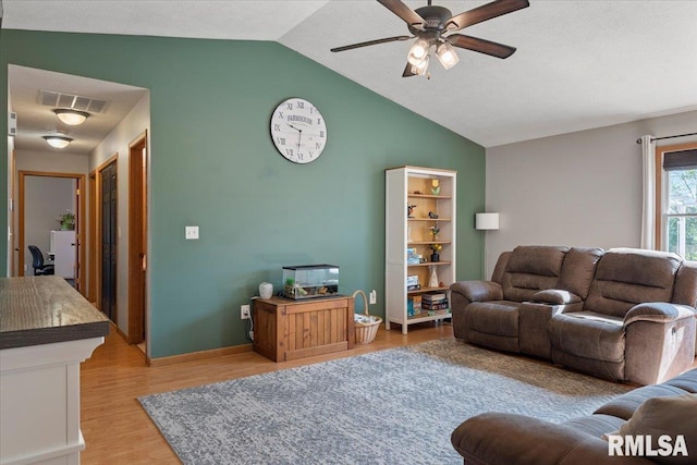 living area featuring ceiling fan, vaulted ceiling, visible vents, and light wood-type flooring