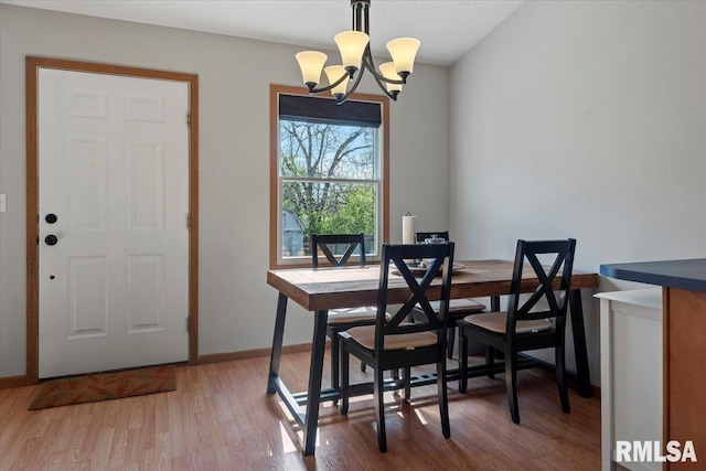 dining room with baseboards, an inviting chandelier, and light wood-style flooring