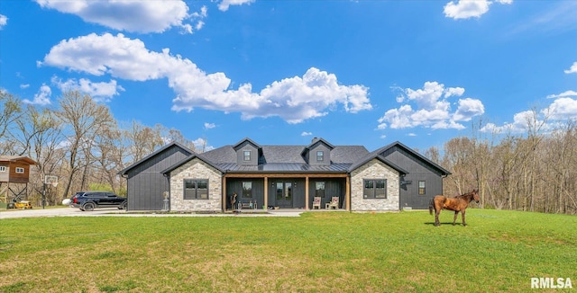 modern farmhouse style home featuring a standing seam roof, a front lawn, metal roof, and stone siding