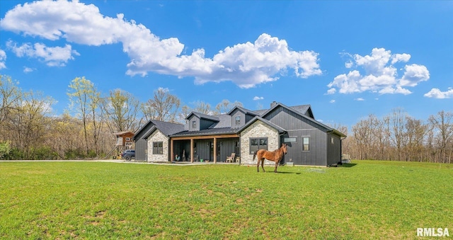 back of property featuring a lawn and stone siding
