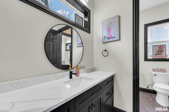 bathroom with baseboards, toilet, and vanity