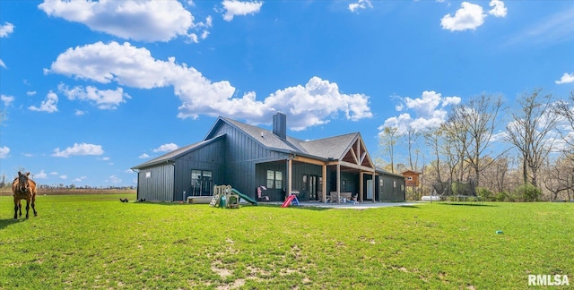 back of house with a yard, a trampoline, a chimney, and a patio area