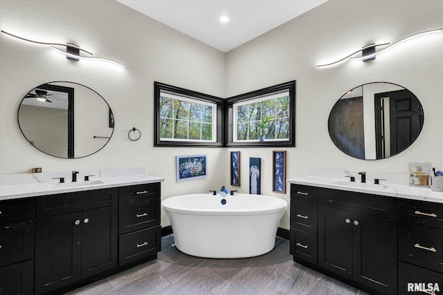 bathroom with two vanities, a freestanding bath, and a sink