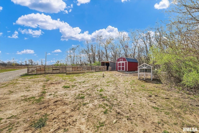 view of yard with fence, an outdoor structure, and a rural view