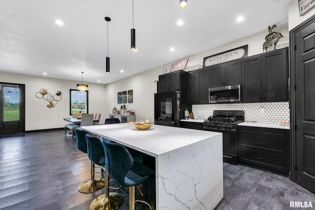 kitchen with tasteful backsplash, a breakfast bar, a center island, black appliances, and dark cabinetry