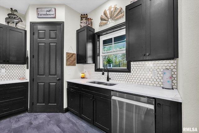 kitchen featuring stainless steel dishwasher, a sink, light stone countertops, dark cabinetry, and backsplash