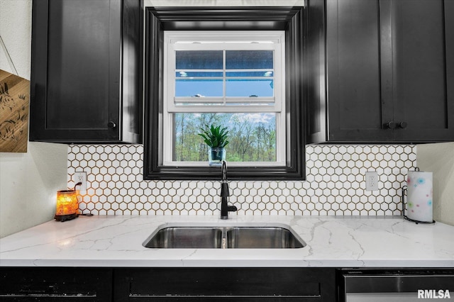 kitchen featuring dishwashing machine, decorative backsplash, dark cabinetry, and a sink