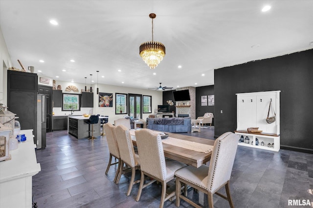 dining space with recessed lighting, a large fireplace, and ceiling fan with notable chandelier