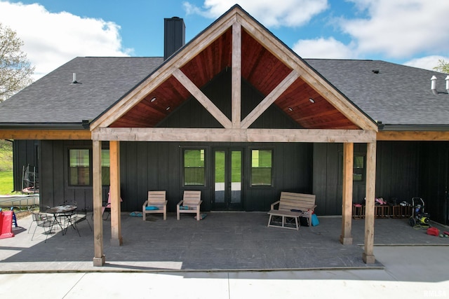 rear view of property featuring a chimney, a shingled roof, french doors, and a patio area