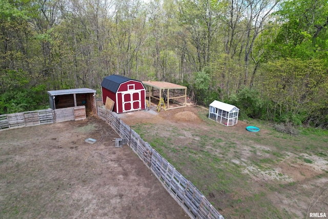 view of yard featuring an outdoor structure, a carport, a shed, exterior structure, and a forest view