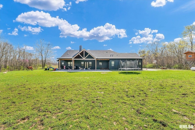 back of property with a yard, a trampoline, and a patio area
