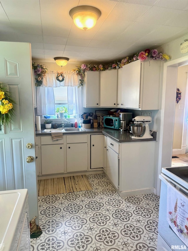 502 E Main St, Plymouth, IL 62367 - kitchen with dark countertops, a sink, white electric range, and white cabinetry