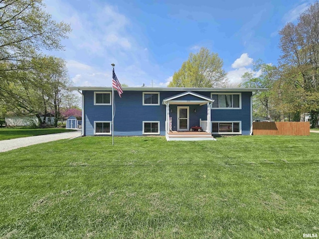 rear view of property featuring a lawn, a shed, and fence