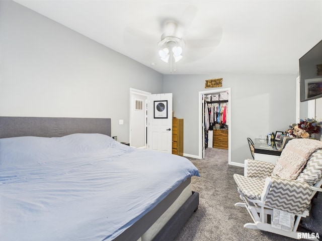 bedroom with carpet flooring, a closet, ceiling fan, a walk in closet, and baseboards