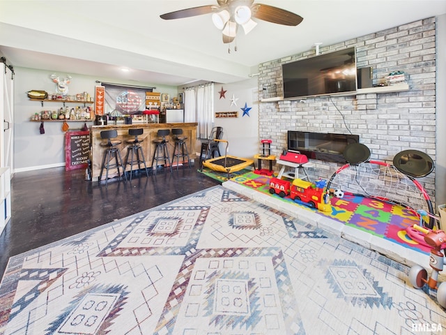 rec room featuring a ceiling fan, baseboards, wood finished floors, and indoor bar