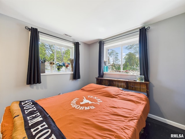 bedroom featuring visible vents, multiple windows, and baseboards