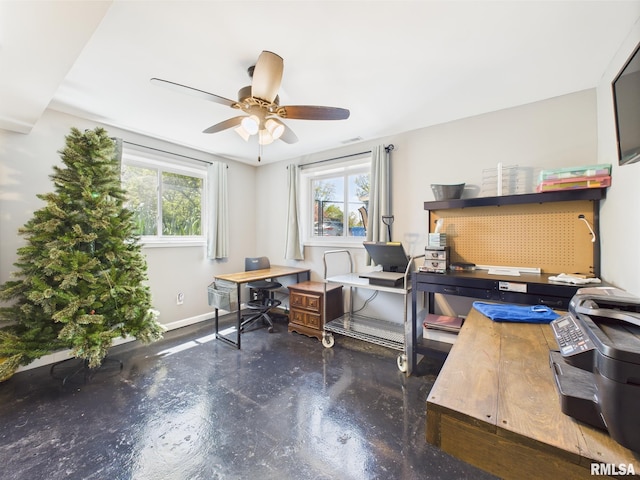 office featuring finished concrete flooring, ceiling fan, plenty of natural light, and baseboards