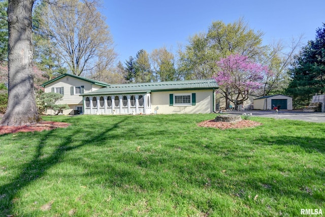 tri-level home featuring a detached garage, an outdoor structure, and a front yard