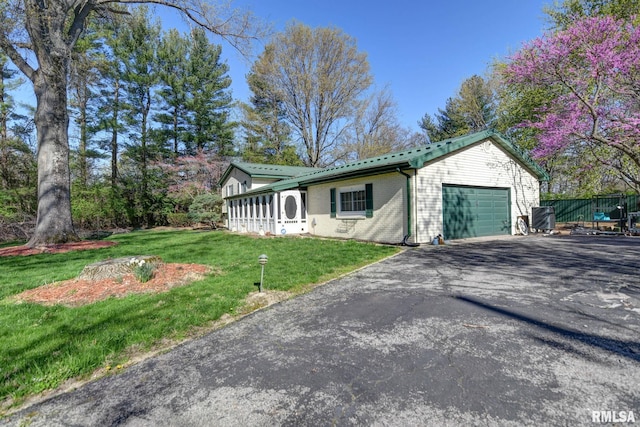 view of front of home with driveway, a garage, a front yard, brick siding, and a sunroom