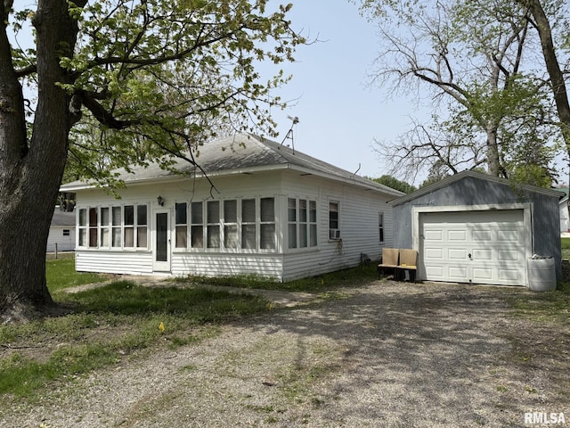 203 N 5th St, Oquawka, IL 61469 - view of front of house featuring an outbuilding, a garage, a shingled roof, and driveway