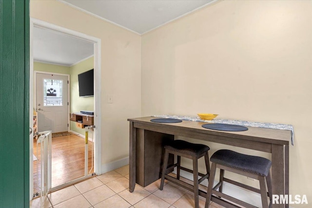 dining room featuring light tile patterned floors, ornamental molding, and baseboards