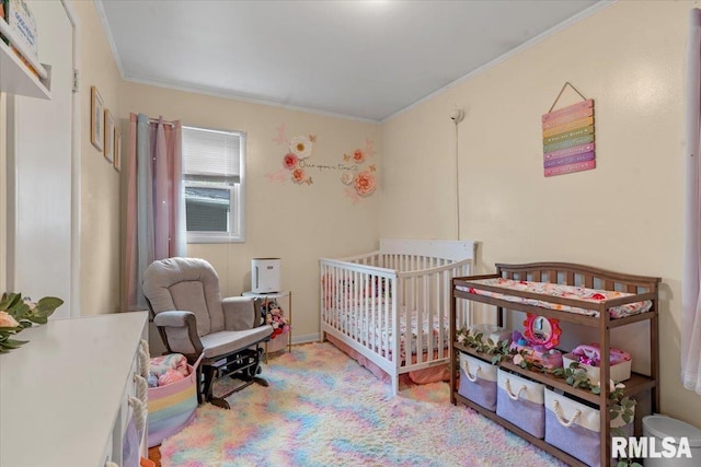 bedroom with a crib and ornamental molding