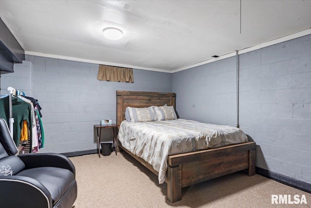 bedroom featuring concrete block wall and light carpet