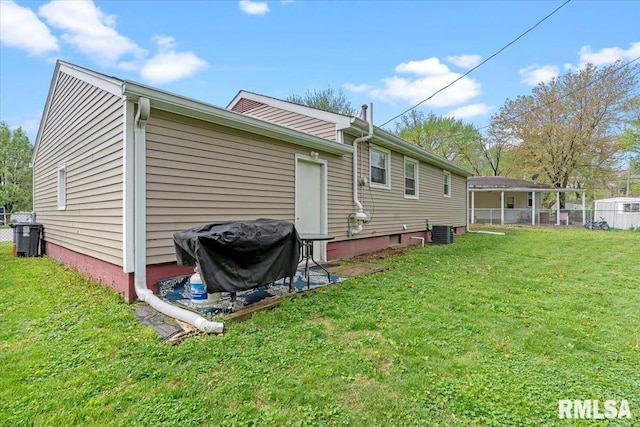 rear view of house with a lawn, fence, and central AC
