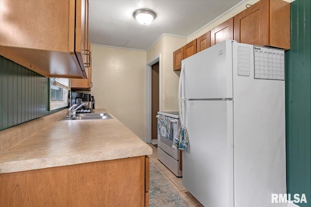 kitchen with brown cabinets, white appliances, light countertops, and a sink