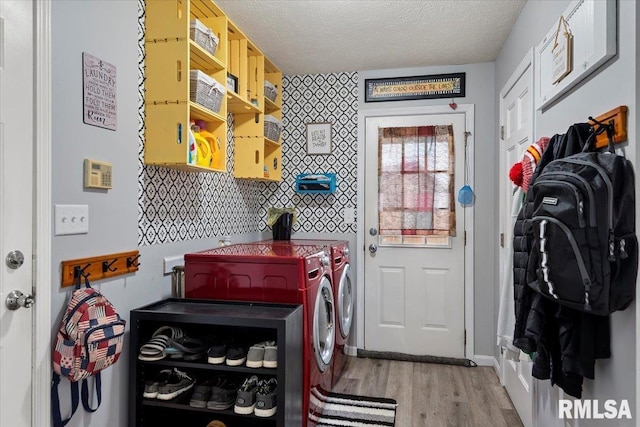 clothes washing area with a textured ceiling, washing machine and clothes dryer, laundry area, and light wood-type flooring