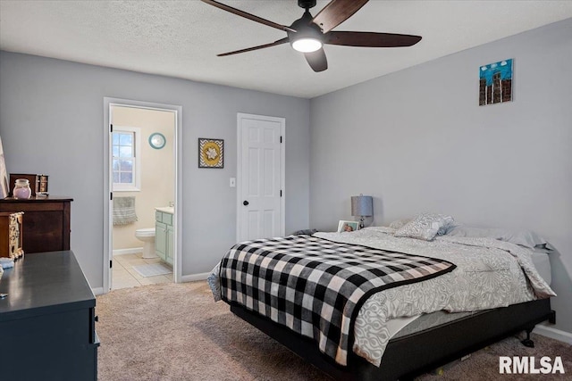 bedroom with a ceiling fan, baseboards, light colored carpet, and ensuite bathroom