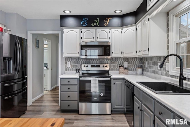 kitchen with white cabinets, a sink, gray cabinetry, black appliances, and backsplash