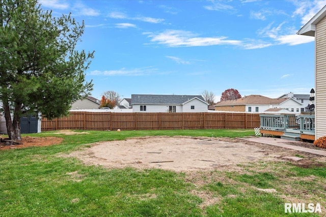 view of yard with a residential view, a wooden deck, an outbuilding, a storage shed, and a fenced backyard