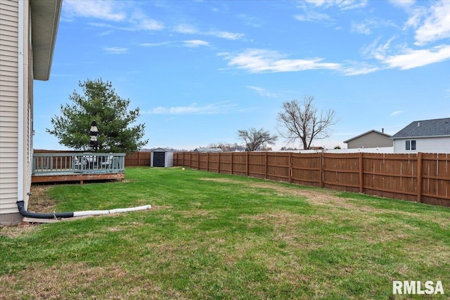 view of yard featuring an outdoor structure, a storage shed, a wooden deck, and a fenced backyard