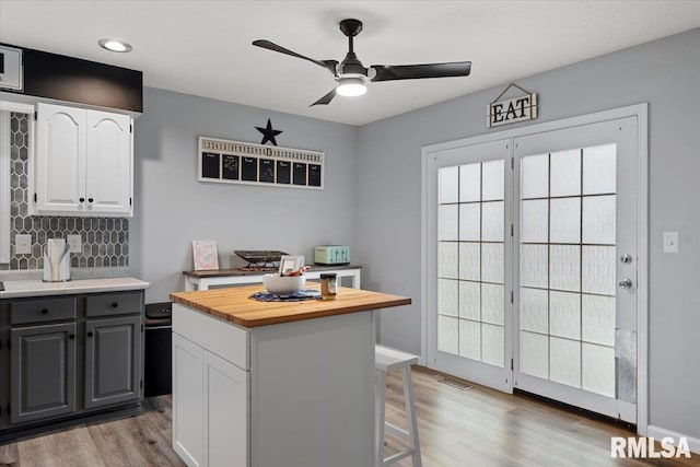 kitchen with white cabinetry, tasteful backsplash, light wood-style flooring, ceiling fan, and wooden counters