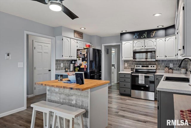 kitchen featuring a sink, stainless steel appliances, ceiling fan, tasteful backsplash, and a breakfast bar area
