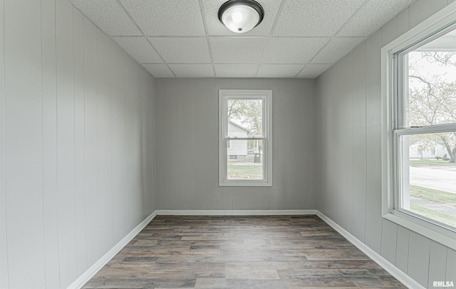 empty room with baseboards, wood finished floors, and a paneled ceiling