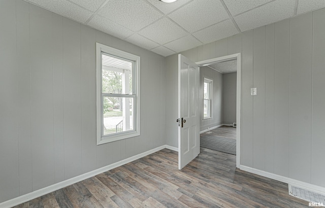 spare room featuring a paneled ceiling, a wealth of natural light, and dark wood-type flooring