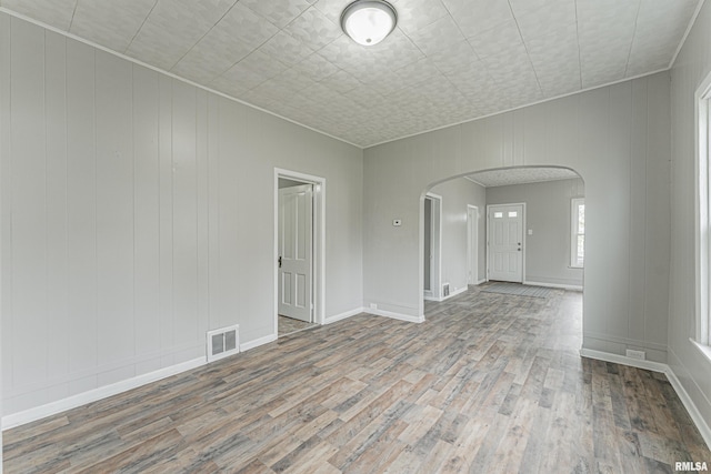 spare room with visible vents, arched walkways, and wood finished floors