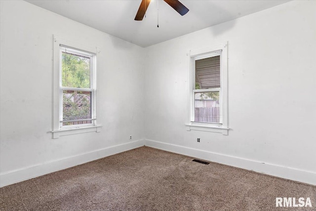 empty room featuring carpet floors, baseboards, a ceiling fan, and visible vents