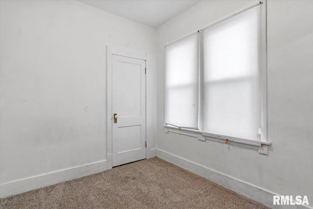 empty room with baseboards, a healthy amount of sunlight, and carpet