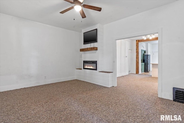 unfurnished living room featuring carpet floors, ceiling fan, and a large fireplace