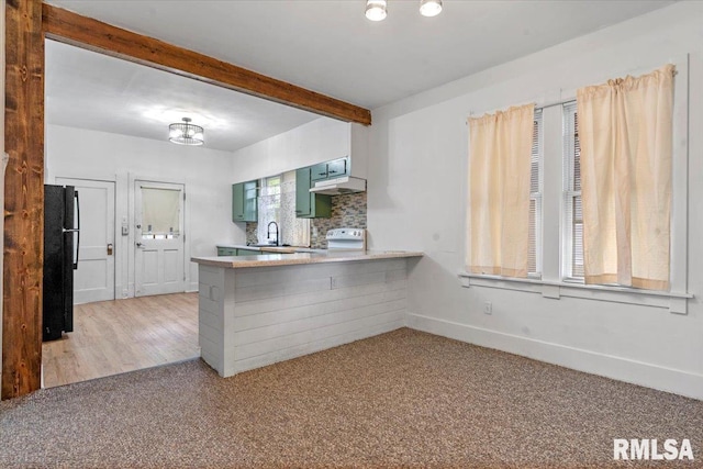 kitchen featuring freestanding refrigerator, a peninsula, beam ceiling, light carpet, and light countertops