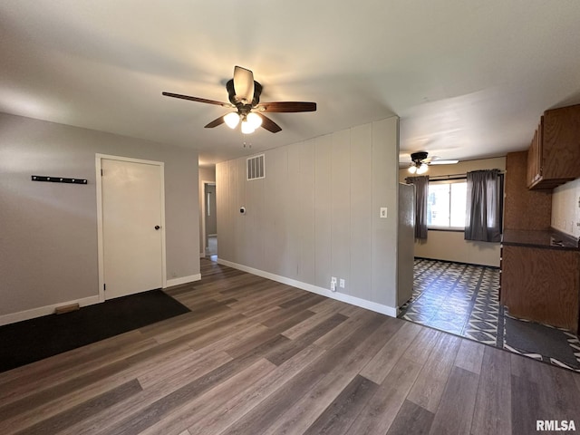spare room with visible vents, a ceiling fan, baseboards, and dark wood-style floors