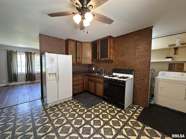 kitchen featuring a ceiling fan, washer / clothes dryer, gas stove, a sink, and white fridge with ice dispenser