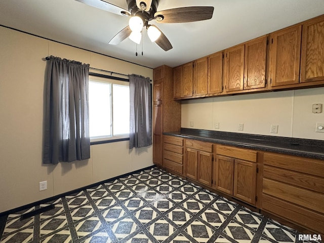 kitchen with brown cabinetry, a ceiling fan, light floors, and dark countertops